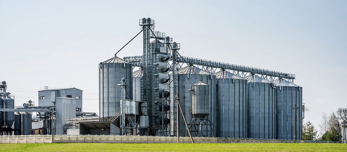 Modern Granary elevator. Silver silos on agro-processing and manufacturing plant for processing drying cleaning and storage of agricultural products, flour, cereals and grain. seed cleaning line