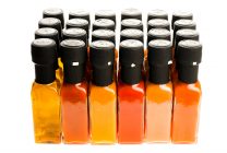 Set of Hot Chili Sauce glass bottles on white background. Different color home made hot sauce in glass bottles. Bottle of chilli sauce and olive oil made with bio eco ingredients. 100ml square bottles